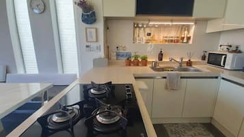 A modern kitchen with a gas stove, microwave, and a small sink.