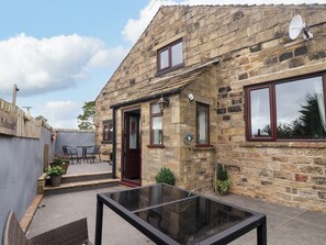 A stone building with a glass table and chairs outside. - Brownhill Bungalow (Keighley)