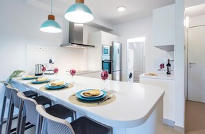 A modern kitchen with a central island, stainless steel appliances, and pendant lighting. - Crystalline - Beach and Dream Rentals (Fuengirola)