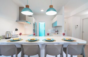 A modern kitchen with a central island, two pendant lights, and a view into the dining area. - Crystalline - Beach and Dream Rentals (Fuengirola)