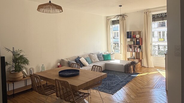Uma sala espaçosa com uma mesa de jantar de madeira, um sofá e uma estante de livros.
