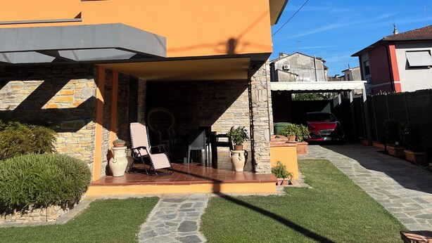Ein modernes Haus mit flachem Dach, einer überdachten Terrasse und einem Natursteinfundament.