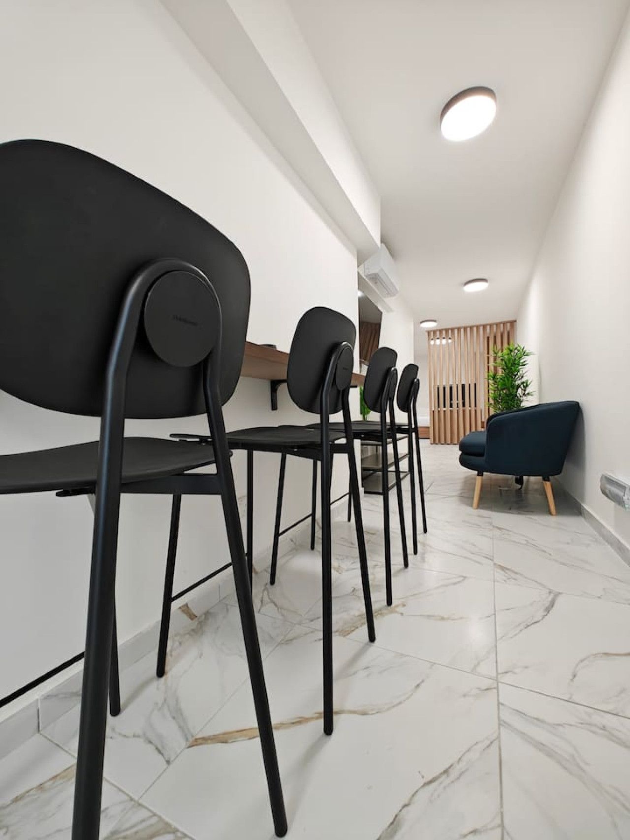 Een modern interieur met een rij zwarte stoelen, een houten receptiebalie en een blauwe bank.