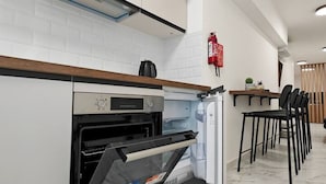 Una cocina moderna con horno empotrado, cafetera y extintor de incendios en la pared.