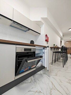 Eine moderne Küche mit eingebautem Backofen, einer Kaffeemaschine und einem an der Wand befestigten Feuerlöscher.