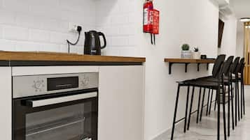 Una cocina moderna con horno empotrado, hervidor y extintor de incendios en la pared.