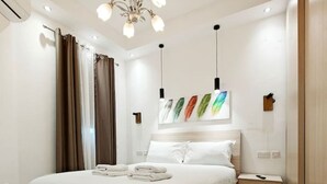 Quarto moderno com uma cama grande, mesa de cabeceira, guarda-roupa, lustre e obras de arte nas paredes.