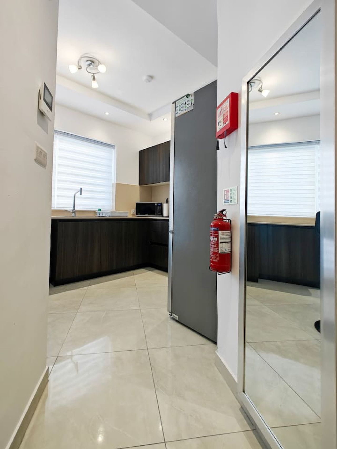 Una cocina moderna con refrigerador, microondas y armarios.