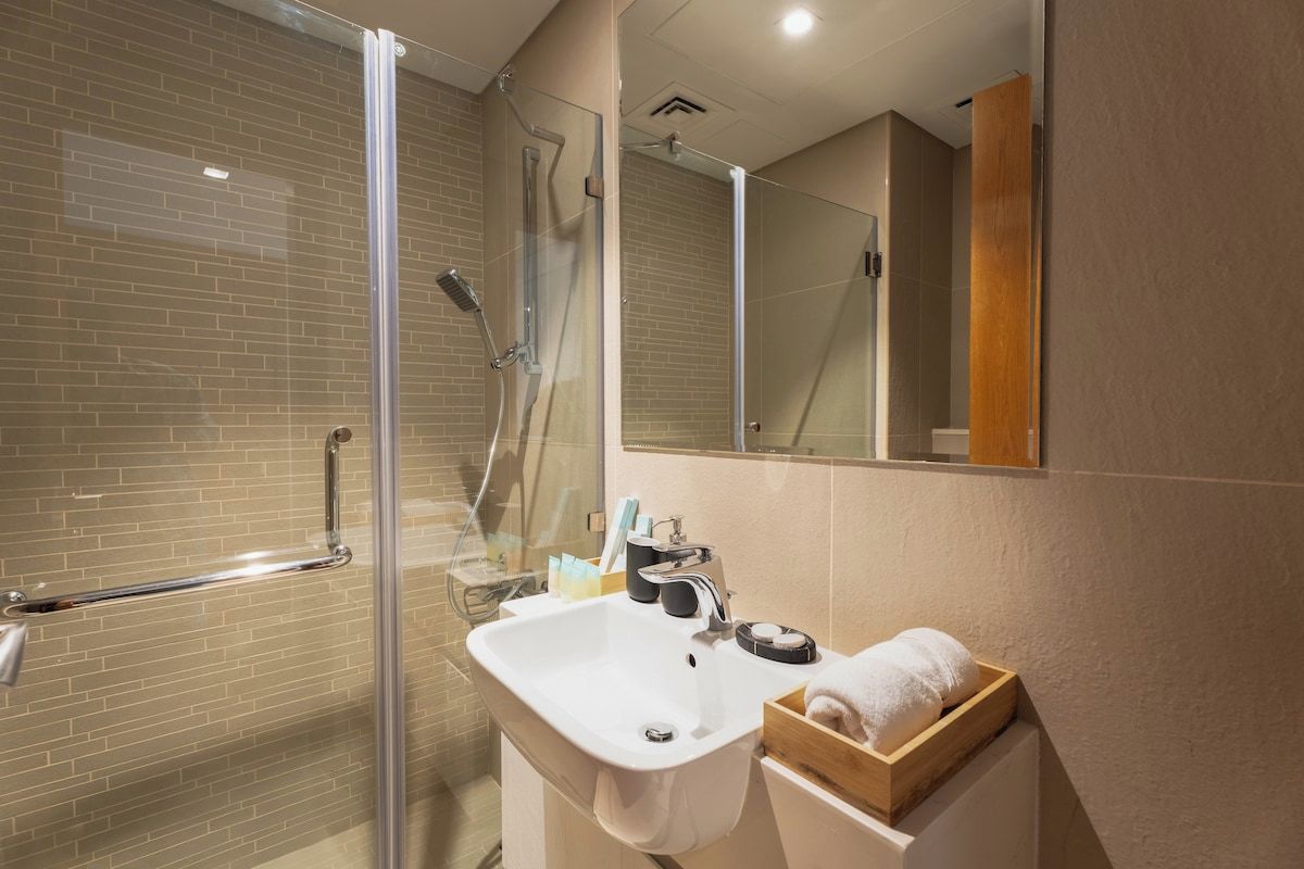 Une salle de bain moderne avec une douche à parois de verre, un lavabo blanc et un meuble-lavabo en bois.