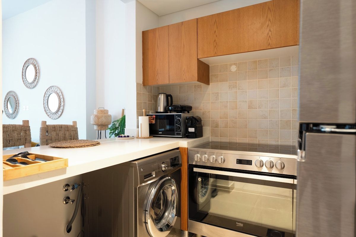 Une cuisine moderne avec des meubles en bois, un four encastré, un four à micro-ondes et un lave-linge.