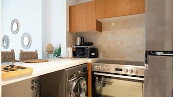 Une cuisine moderne avec des meubles en bois, un four encastré, un four à micro-ondes et un lave-linge.