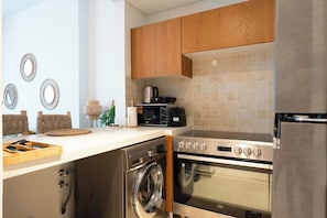 Une cuisine moderne avec des meubles en bois, un four encastré, un four à micro-ondes et un lave-linge.
