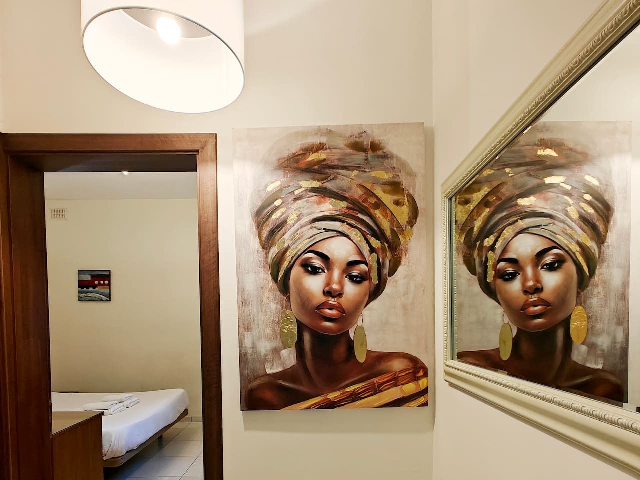 A room with a bed, a painting on the wall, and a mirror.
