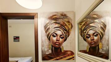 A room with a bed, a painting on the wall, and a mirror.