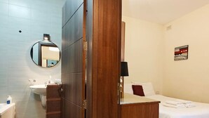 Une chambre d’hôtel avec un paravent en bois, un lit, une table de chevet, un miroir, un lavabo et des toilettes.