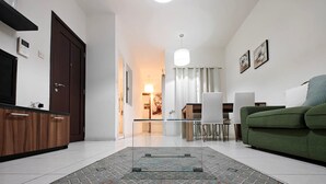 Un salon moderne avec une table basse en verre, un canapé vert et un tapis à motifs.