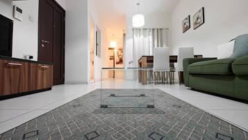 Ein modernes Wohnzimmer mit einem Glastisch, einem grünen Sofa und einem gemusterten Teppich.