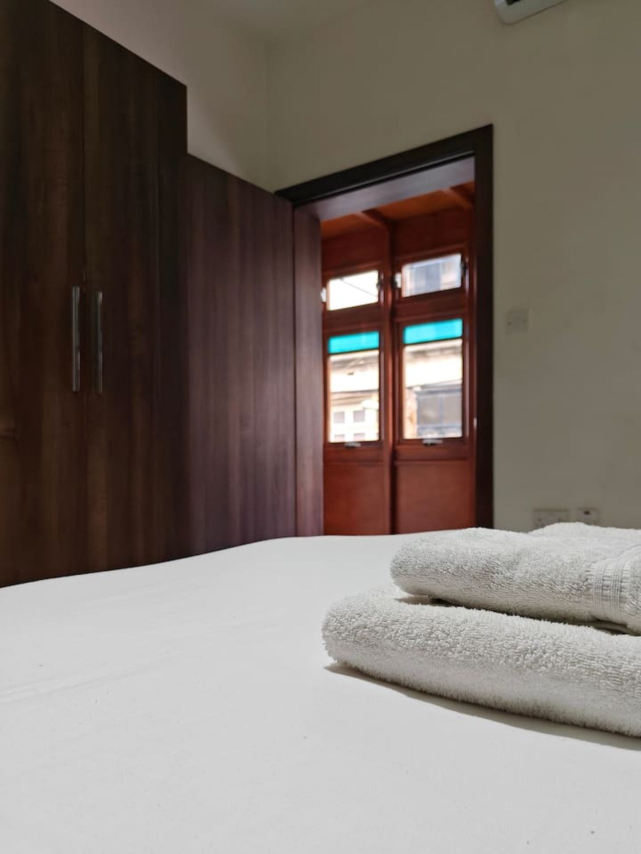 Ein Schlafzimmer mit einem Bett, einem Holzschrank und einer Tür zu einem Außenbereich.