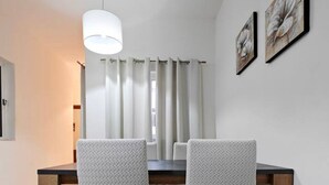 Un espace repas comprenant une table, des chaises et un luminaire suspendu.