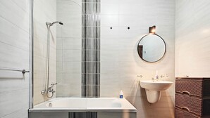 Une salle de bain moderne avec une baignoire sur pieds, un lavabo fixé au mur et un miroir.