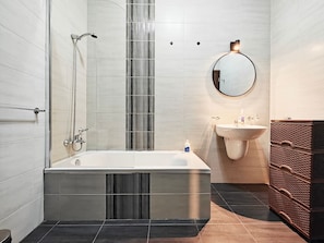 Ein modernes Badezimmer mit einer freistehenden Badewanne, einem wandmontierten Waschbecken und einem Spiegel.