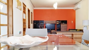 A modern interior with a glass dining table, chairs, and a kitchen area in the background. - Ivy 2 bedroom apartment (Swieqi)