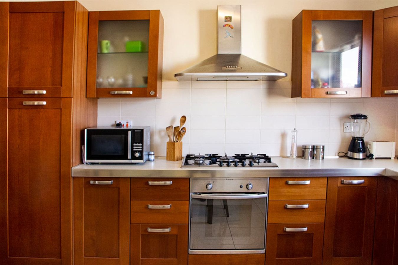 Une cuisine avec des armoires en bois, un four à micro-ondes, une cuisinière et un mixeur.