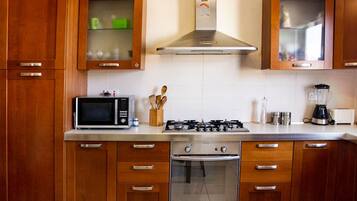 Une cuisine avec des armoires en bois, un four à micro-ondes, une cuisinière et un mixeur.