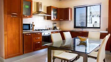 A modern kitchen with wooden cabinets, a glass dining table, and a large window.