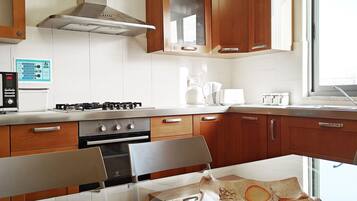 A modern kitchen with wooden cabinets, stainless steel appliances, and a glass dining table.