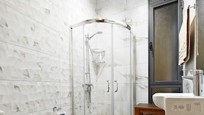A bathroom with a glass-enclosed shower, a toilet, a sink, and a wooden cabinet. - Ivy 2 bedroom apartment (Swieqi)