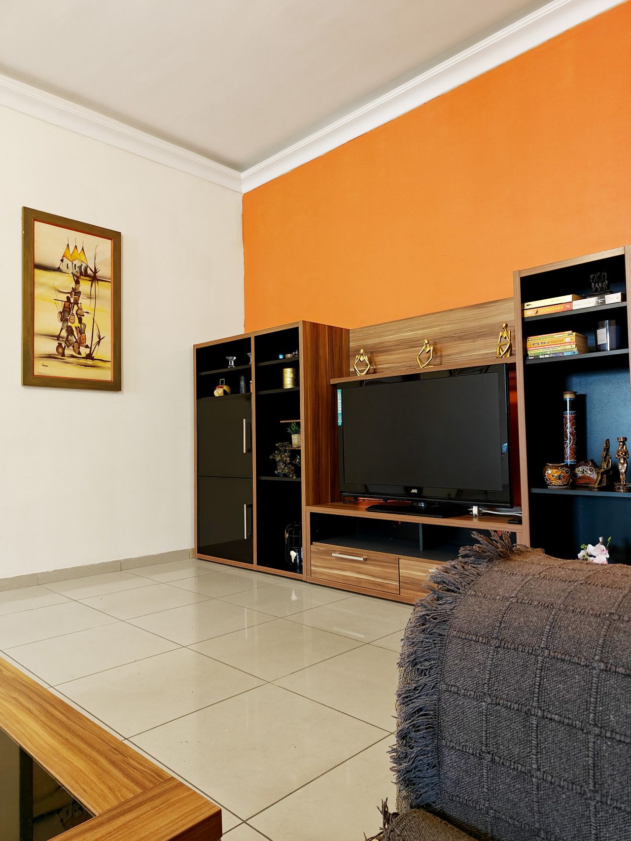 Un salon équipé d’un téléviseur à écran plat, d’un meuble de rangement en bois et d’un tableau accroché au mur.