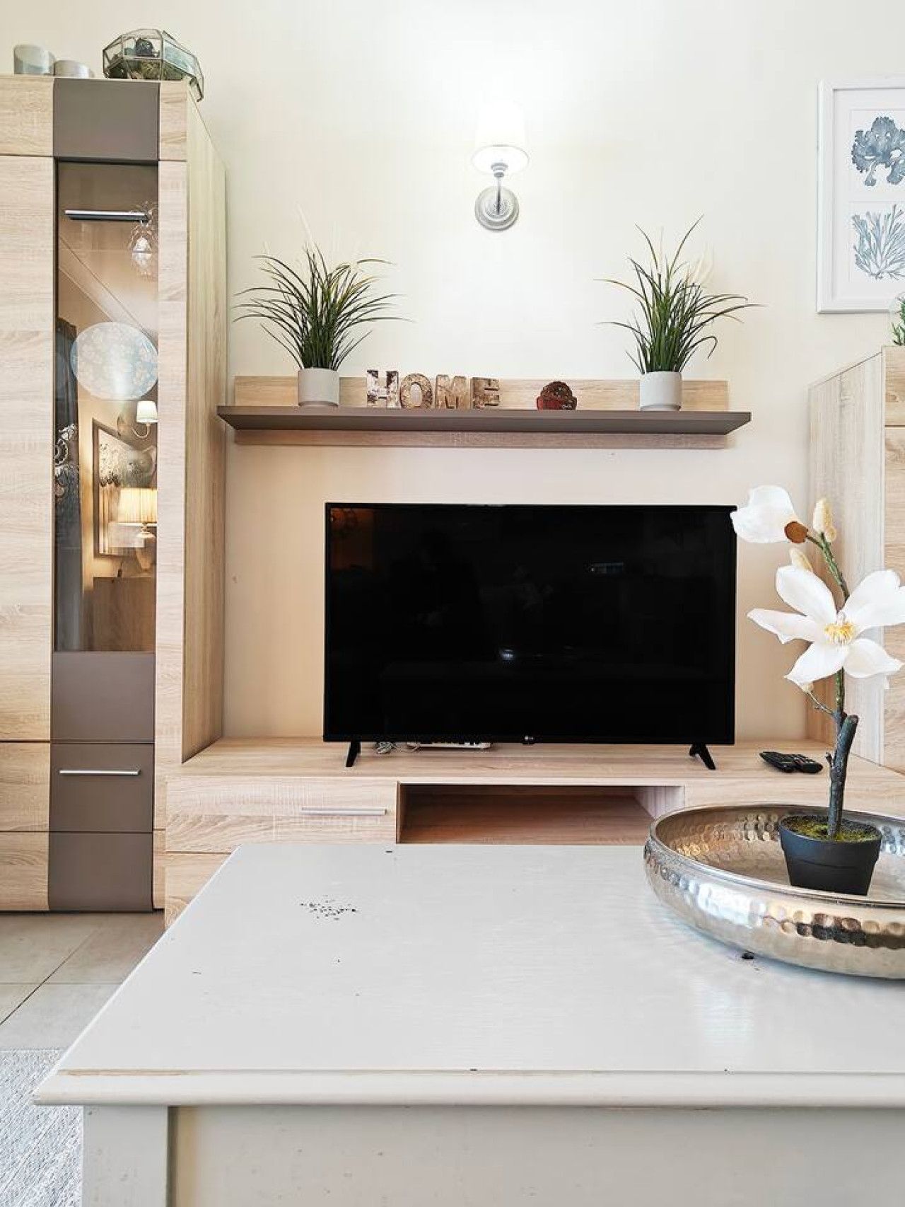 Ein Wohnzimmer mit Flachbildfernseher, Holzschränken, Kamin und Zimmerpflanzen.