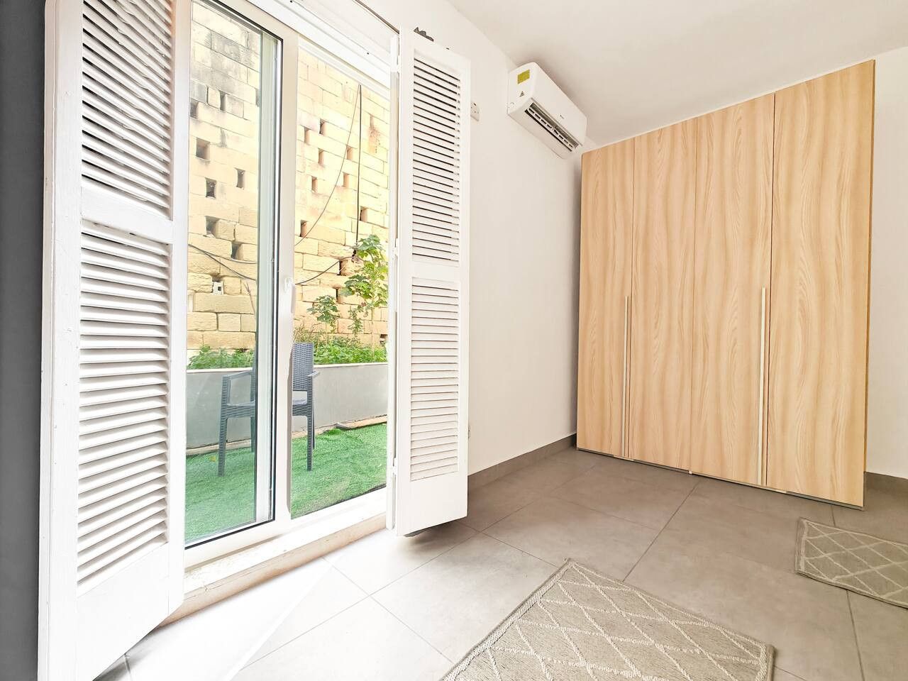 A room with a sliding glass door, a wooden wardrobe, and a tiled floor.