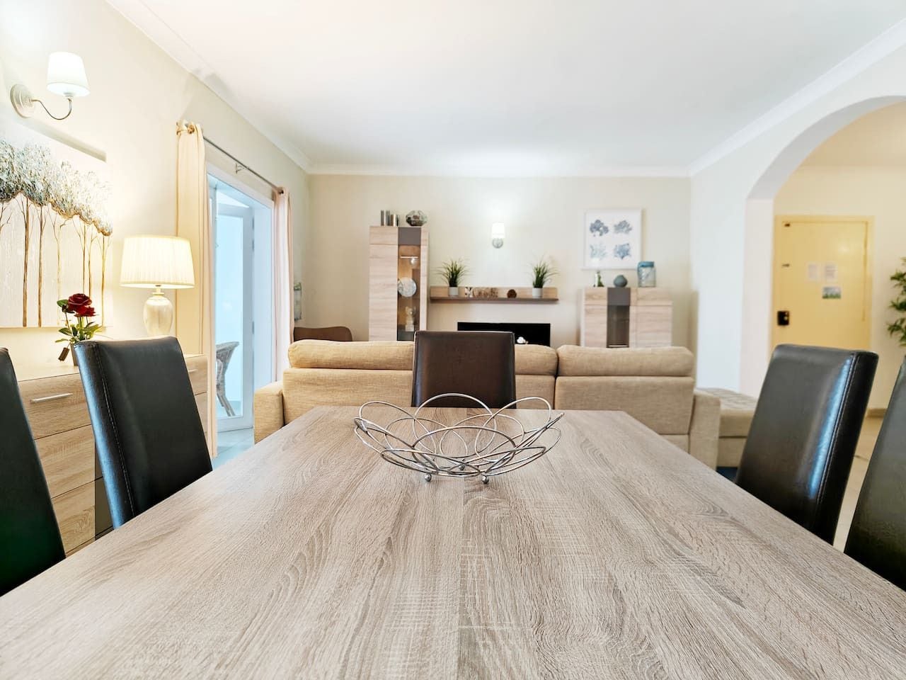 A dining area with a wooden table, black chairs, and a decorative metal centerpiece.
