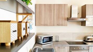 A modern kitchen with wooden cabinets, a stainless steel sink, a microwave, a toaster, and a built-in oven.