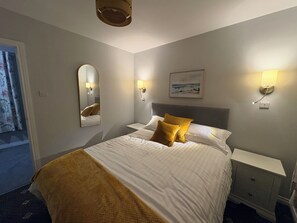 Una camera d'albergo con un letto, comodini, uno specchio, luci a parete e un quadro.