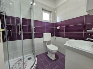 Un baño con ducha envuelta en vidrio, inodoro y lavamanos.