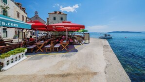 Ein Küsten-Café mit Terrassensitzgelegenheiten, ein Boot im Wasser und freier Meerblick.