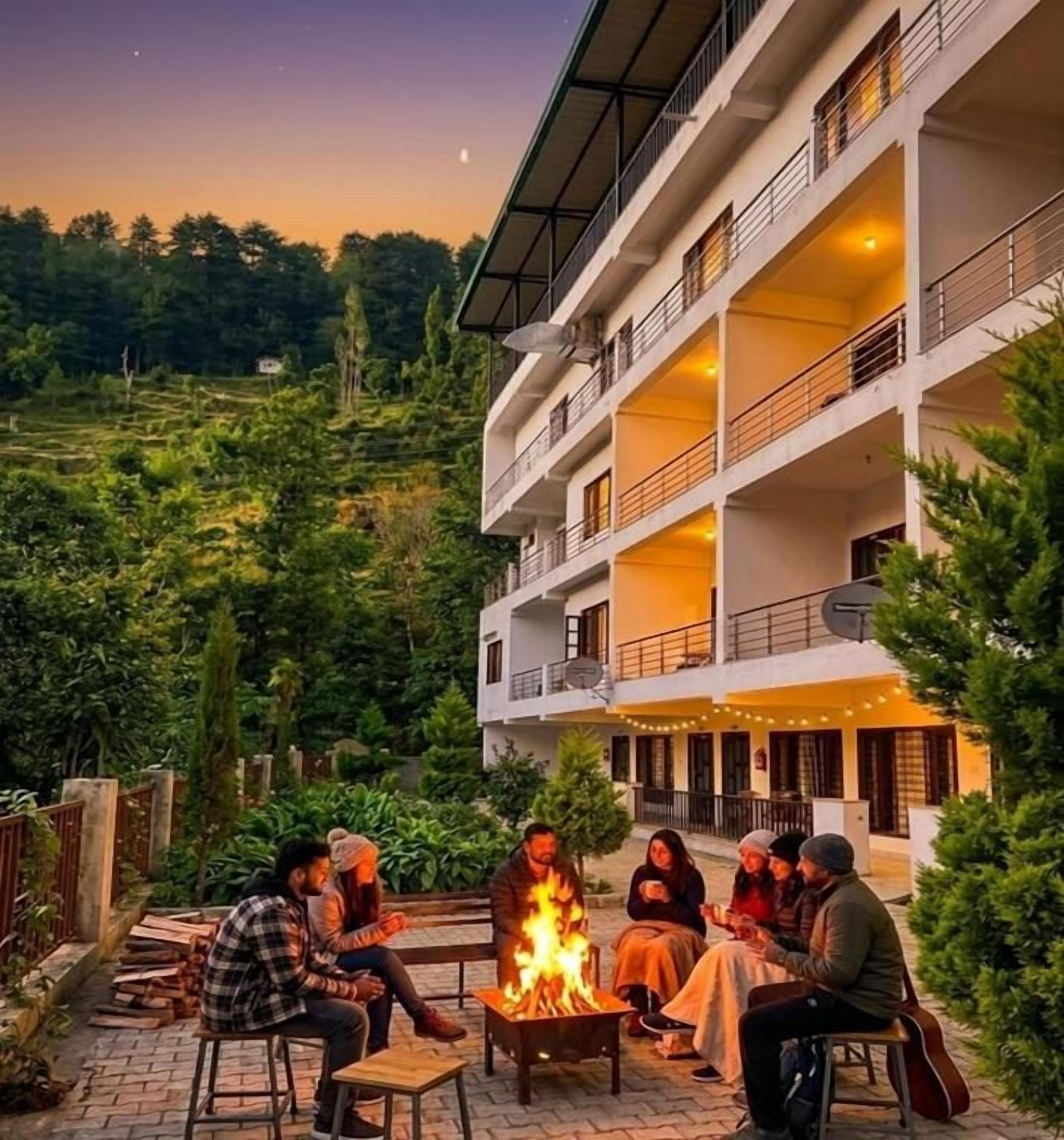 A multi-story building with outdoor seating areas and a fire pit.