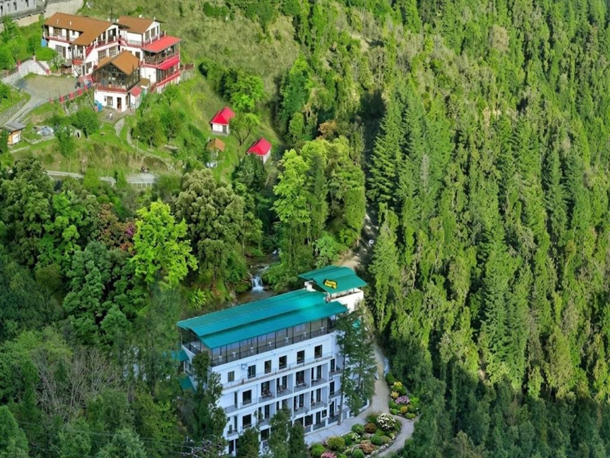 Ein mehrstöckiges Gebäude mit Gründach, umgeben von dichtem Wald.
