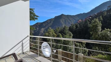 A balcony with a view of a mountainous landscape, a satellite dish, and a railing.