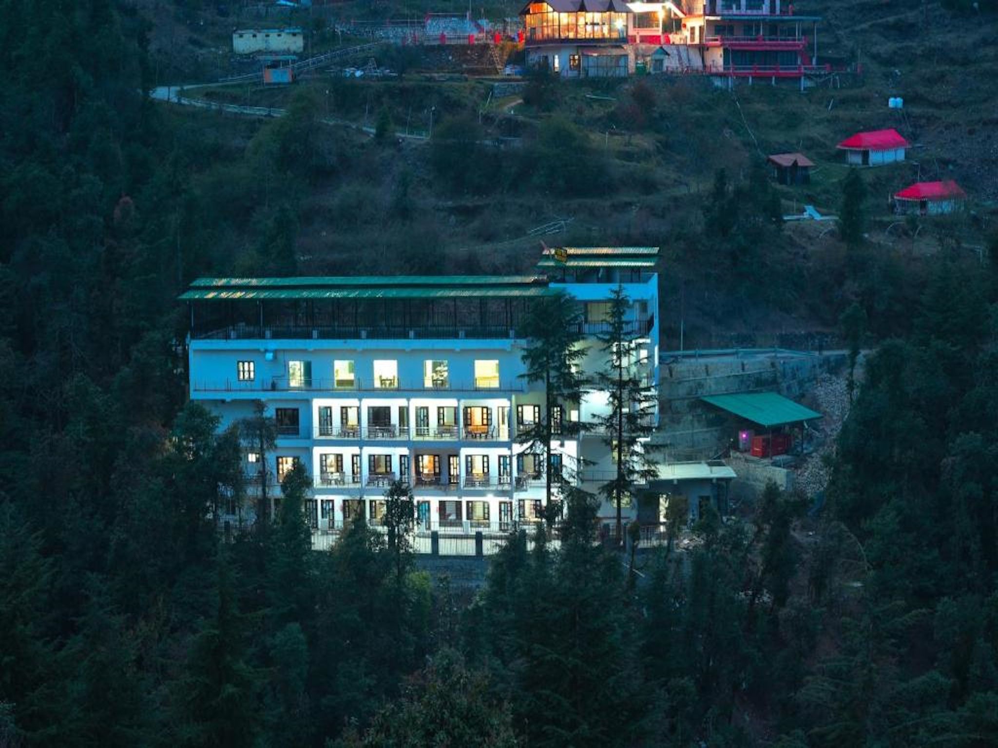 A multi-story building with balconies, surrounded by dense forest.