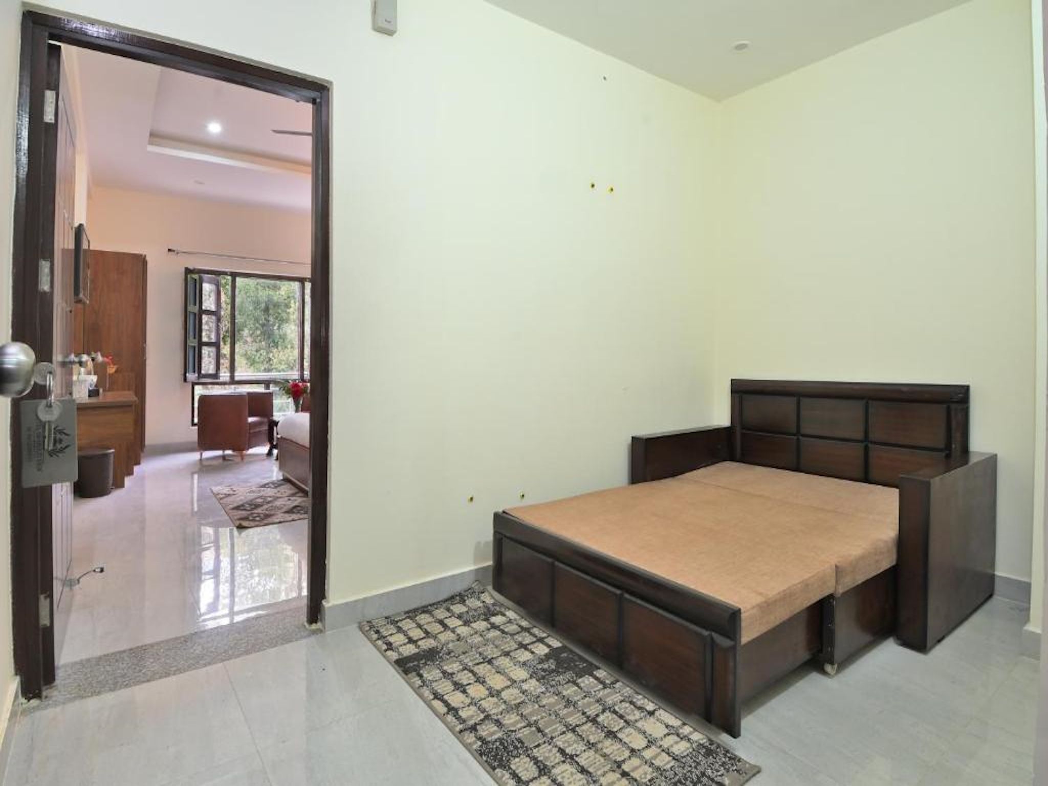 Un dormitorio con cama, puerta, ventana y vista a otra habitación.