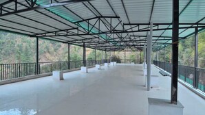 An empty covered walkway with a metal roof and railings, surrounded by greenery. - LA Riqueza Dhanolti (Dhanolti)