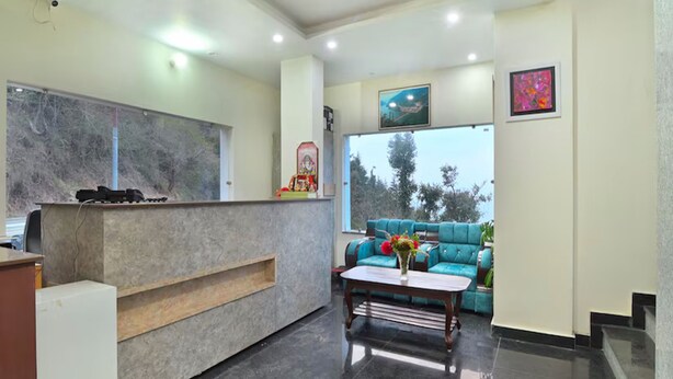 A reception area with a marble counter, a blue sofa, and a coffee table with flowers. - LA Riqueza Dhanolti (Dhanolti)