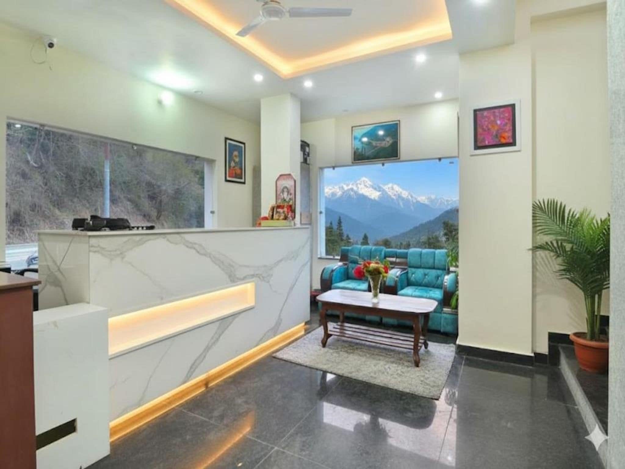 A modern reception area with a marble reception desk, a sofa with a mountain view, and a ceiling fan.