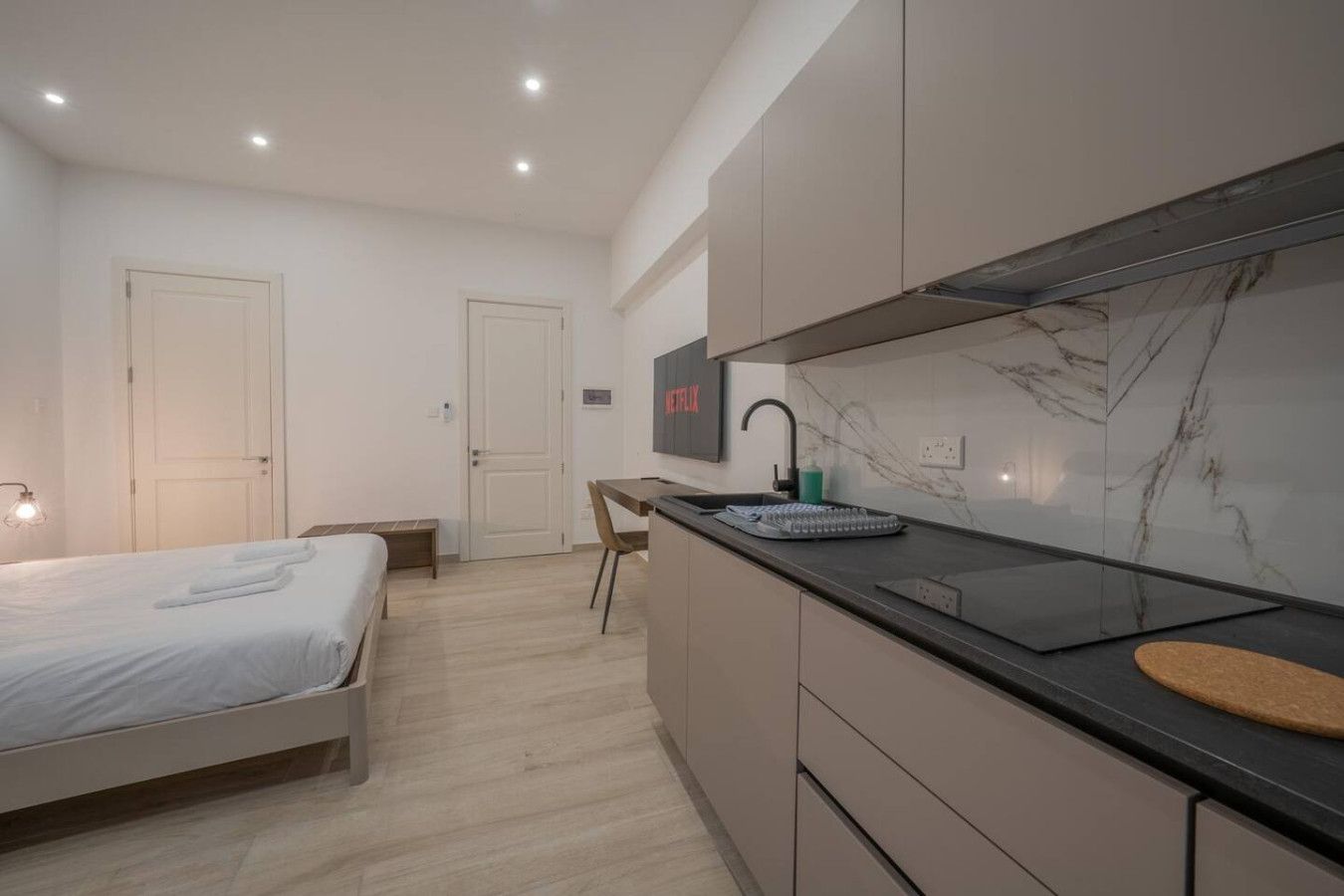 Una camera da letto moderna con un letto, un comodino e una scrivania con sedia.