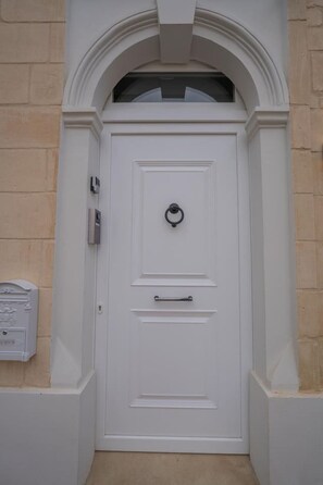 Una puerta blanca con un aldabón, buzón y manija.