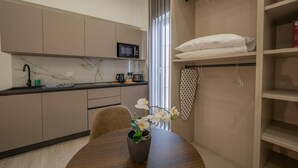 A modern kitchen with a microwave, a coffee maker, and a sink. There is a dining table with a vase of flowers. - Urban Vibe 3 apartment (Kirkop)